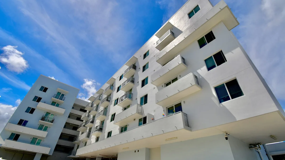 Bright white residential building exterior against a blue sky